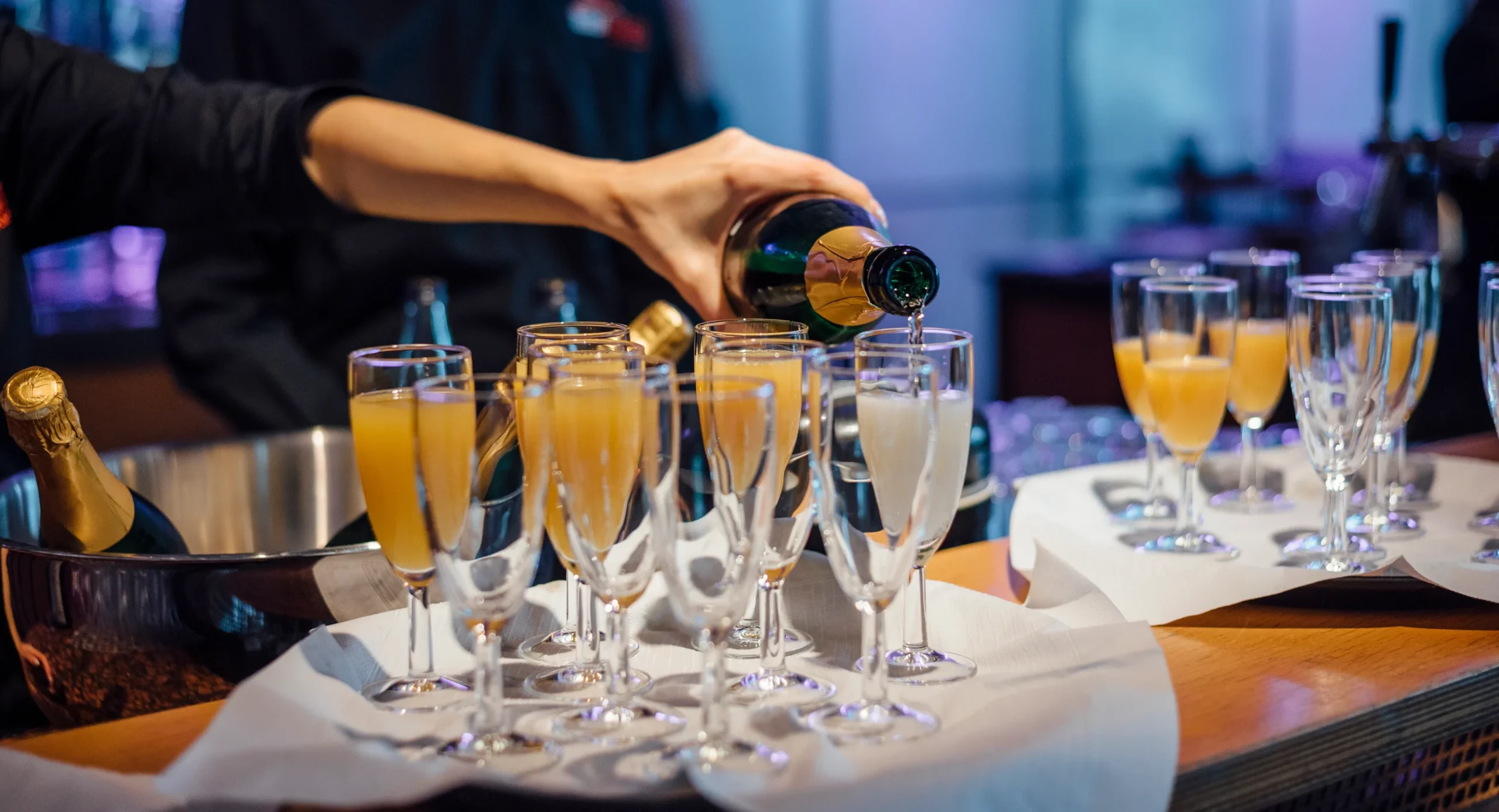 Servicekraft schenkt Sekt und Orangensaft in Gläser bei einem stilvollen Empfang von Tafelfreuden in Köln ein