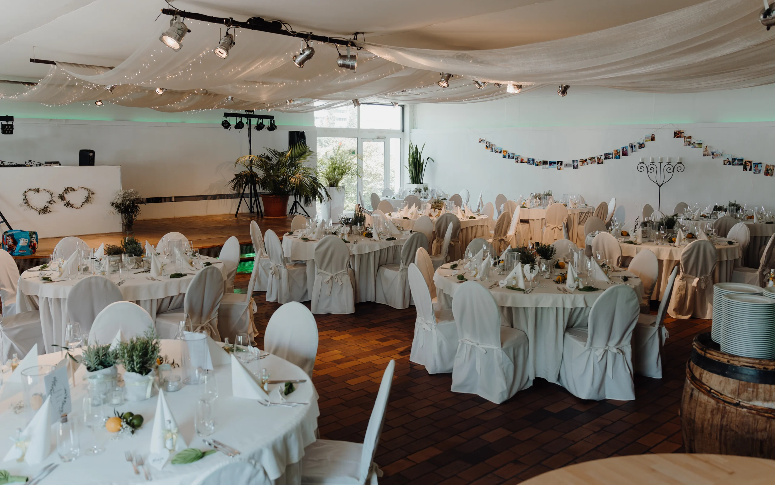 Hochzeitssaal der Eventlocation Tafelfreuden in Köln mit weißen Stuhlhussen, runden Tischen und eleganter Dekoration